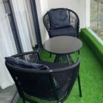 Black woven bistro set with two chairs and a round table on green turf.